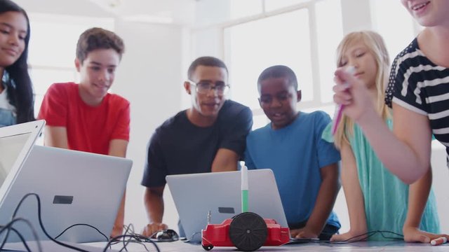 Students With Male Teacher In After School Computer Coding Class Learning To Program Robot Vehicle
