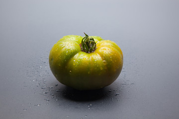 Tomate verde sobre fondo gris