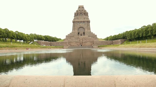 Memorial in Leipzig Battle Of Nations Monument. An outstanding architectural building of city. A popular place to visit tourists. Camera approaches moving toward granite statue in front of which lake