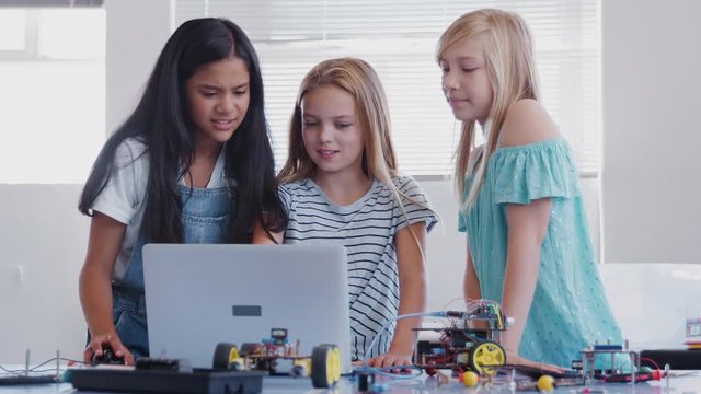 Three Female Students Building And Programing Robot Vehicle In After School Computer Coding Class 