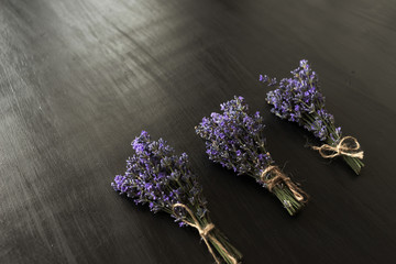 Three fragrant violet lavender bouquets on a dark background tied with decorative thread.