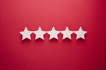 Feedback concept. Five white paper stars of approval on a red background.