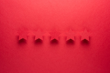 Feedback concept. Five red paper stars of approval on a red background.