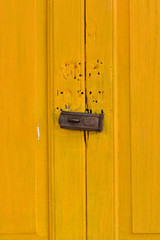 Full frame of yellow color of old wooden door with a crack locked