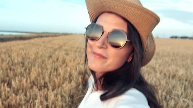 Smiling face fashion travel woman running on wheat field and turning head at sunset enjoying freedom