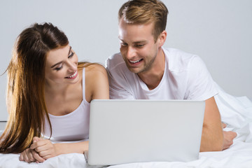 Couple using laptop, on bed