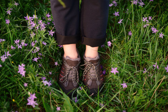 Low section of woman wearing Hiking boots while standing on pink flowe