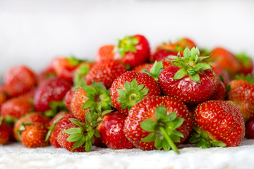 Lots of fresh ripe red strawberries on the white table. Home garden harvesting