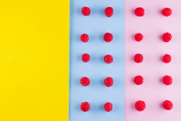 Pattern of raspberries on multicolored background. Colorful diet and healthy food concept. Background of raspberries. Top view. Flat lay. Copy space