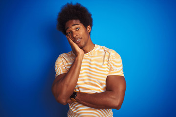 Fototapeta na wymiar American man with afro hair wearing striped yellow t-shirt over isolated blue background thinking looking tired and bored with depression problems with crossed arms.
