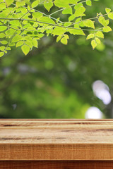 Wooden desk and green leaf nature background.