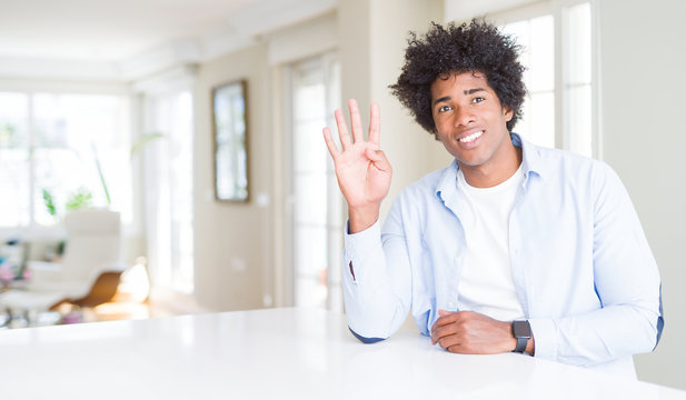 African American man at home showing and pointing up with fingers number four while smiling confident and happy.