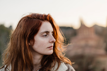 Young beautiful woman looking melancholic with city view behind