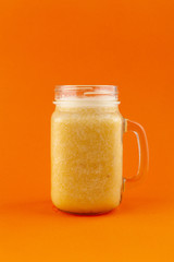 Exotic smoothie with banana, mango and orange, isolated on bright background