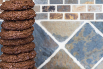 A stack of freshly baked homemade chocolate chip brownie cookies; A very tall pile of chocolate cookies, piled high