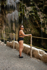 Pretty woman wearing dark glasses next to the rock formations and the waterfall of Tolantongo Hidalgo Mexico half body