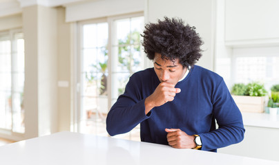 Young african american man wearing casual sweater sitting at home feeling unwell and coughing as symptom for cold or bronchitis. Healthcare concept.