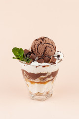 Layered ice cream dessert with twicks, caramel topping and whipped cream, isolated on pastel background