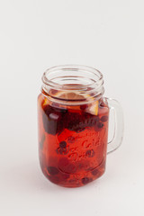 Red herbal tea with cranberry, blueberry, strawberry, lemon and honey isolated on white background as a perfect autumn drink