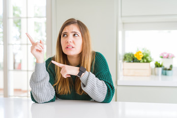 Young beautiful plus size woman wearing casual striped sweater Pointing aside worried and nervous with both hands, concerned and surprised expression