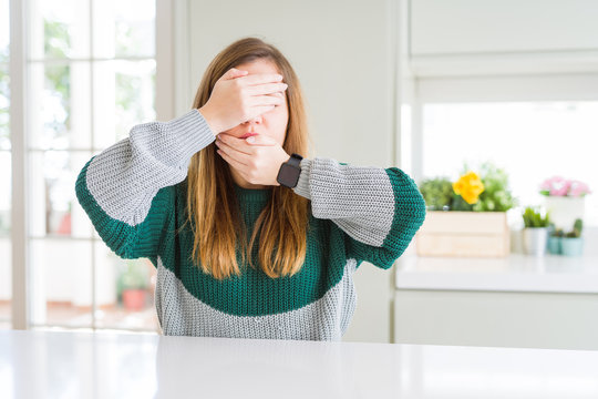 Young beautiful plus size woman wearing casual striped sweater Covering eyes and mouth with hands, surprised and shocked. Hiding emotion