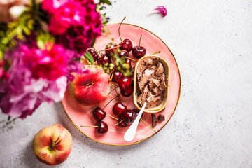 Beautiful pink food background. Flowers, chocolate dessert and berries on pink plate.