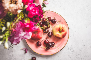 Beautiful pink food background. Flowers and berries on pink plate.