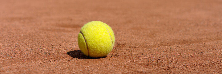 yellow tennis ball on clay court, panoramic photo