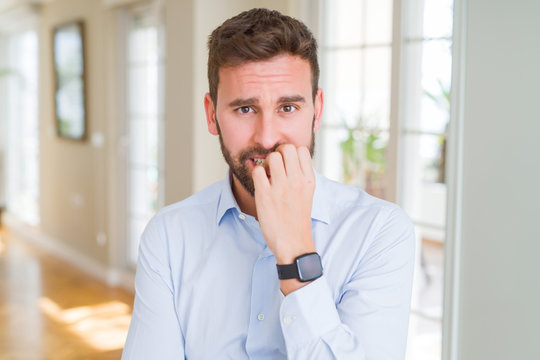 Handsome business man looking stressed and nervous with hands on mouth biting nails. Anxiety problem.