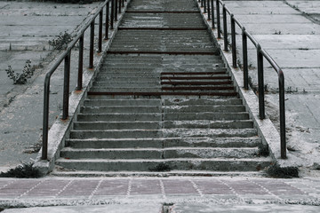 Old broken concrete staircase with metal handrails