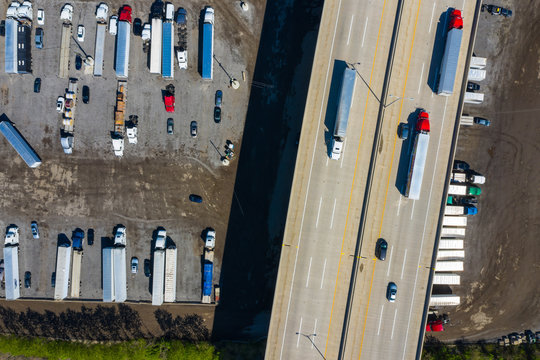 Aerial view of parked semi trucks and cars underneath a freeway at a parking lot in Romeoville, IL - USA