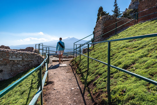 Taormina, Sicily - Tourist in the ruins of the Greek Theater, Enta volcano in the background