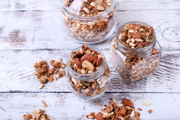 Granola with nuts in glass jars on the white wooden table