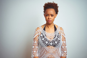 Young african american woman with afro hair wearing a bikini over white isolated background skeptic and nervous, frowning upset because of problem. Negative person.