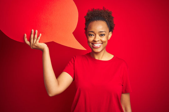 Young african american woman holding speech bubble over red isolated background with a happy face standing and smiling with a confident smile showing teeth