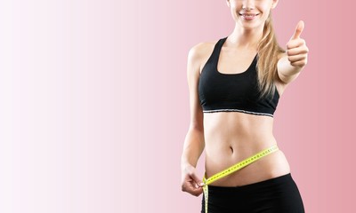 Slim young woman measuring her thin waist