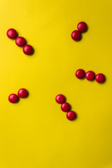 Naklejka na ściany i meble Shape with red candy on a yellow background.