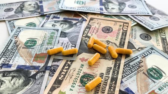 Expensive medicine. Pills of different colors on money background
