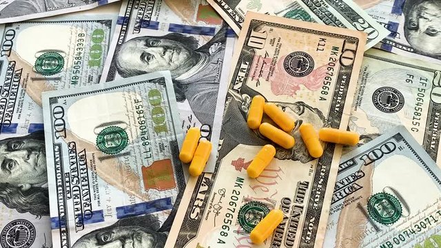 Expensive medicine. Pills of different colors on money background