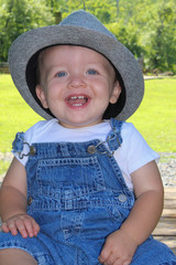 little boy in a hat and overalls