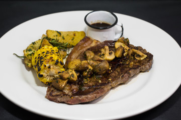 Grilled vegetables and beef steak on white plate. 