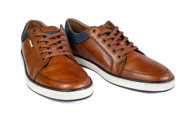 A pair of brown leather trainers on a white background.