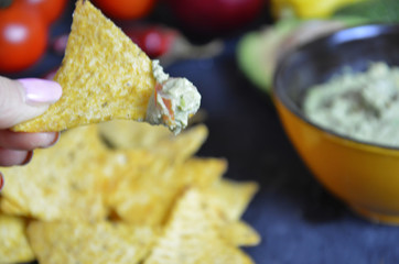 Mexican corn chips nachos with salsa dip on a black background with guacamole sauce, avacoda with lime and hot pepper