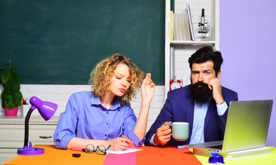 Serious teachers couple in classroom. Girl student with bearded teacher in auditorium. University students at college. Learning, education concept. Bearded teacher with female student in classroom.