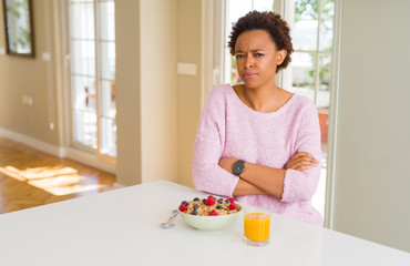 Young african american woman having healthy breakfast in the morning at home skeptic and nervous,...