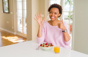 Young african american woman having healthy breakfast in the morning at home showing and pointing up with fingers number six while smiling confident and happy.