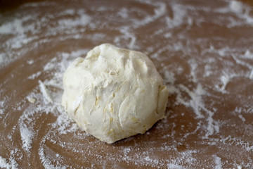 Ball of dough with flour on parchment paper. Selective focus.