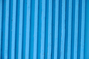 The surface of the old door of wooden planks painted blue paint