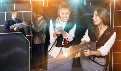 Emotional portrait of two women holding laser pistols and playin