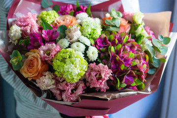 florist holding a colorful bouquet of flowers in her hands floral background